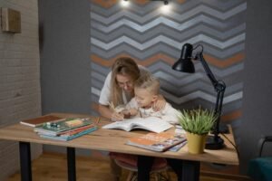 A mother assists her son with homework at a desk, fostering a learning environment.